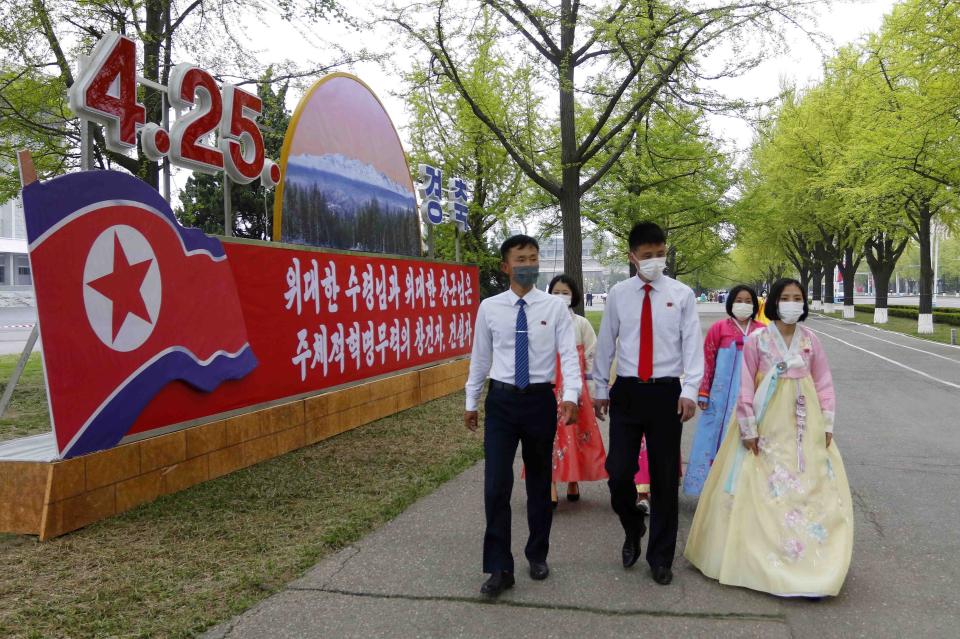 Citizens walk past celebrative posters displayed on the 90th founding anniversary of the Korean People's Revolutionary Army in Pyongyang, North Korea, Monday, April 25, 2022. The poster reads "Historic root of our revolution". (AP Photo/Jon Chol Jin)