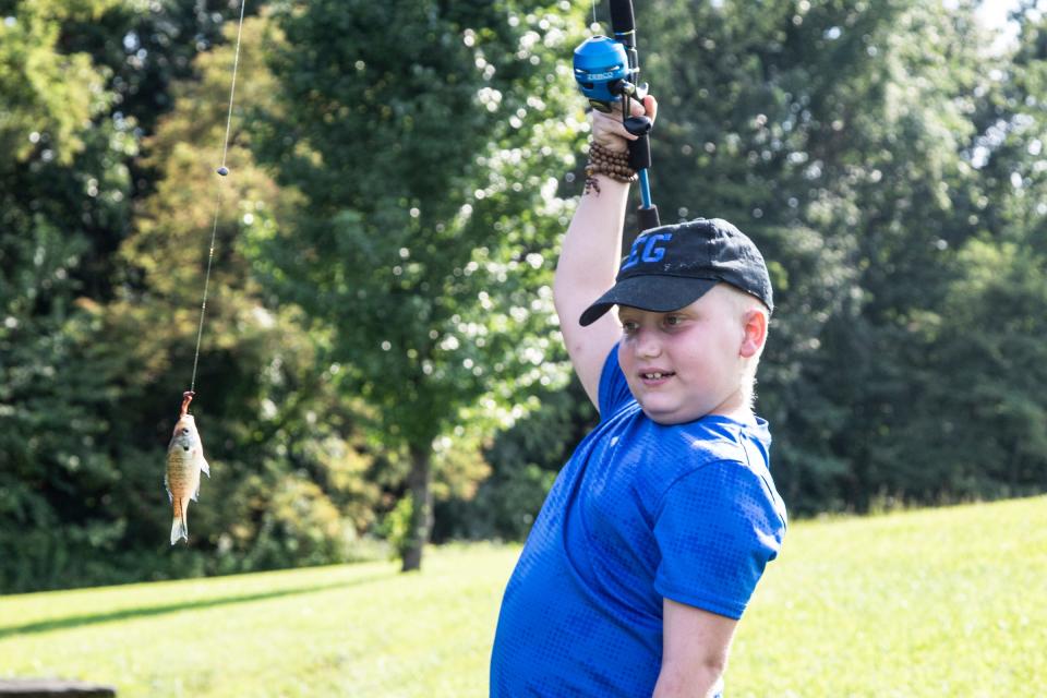 RJ waits for his mom to help remove a fish he caught at his cousin’s pond in Piketon, Ohio, Thursday afternoon. Even in his condition, his mom tries to do normal activities. 