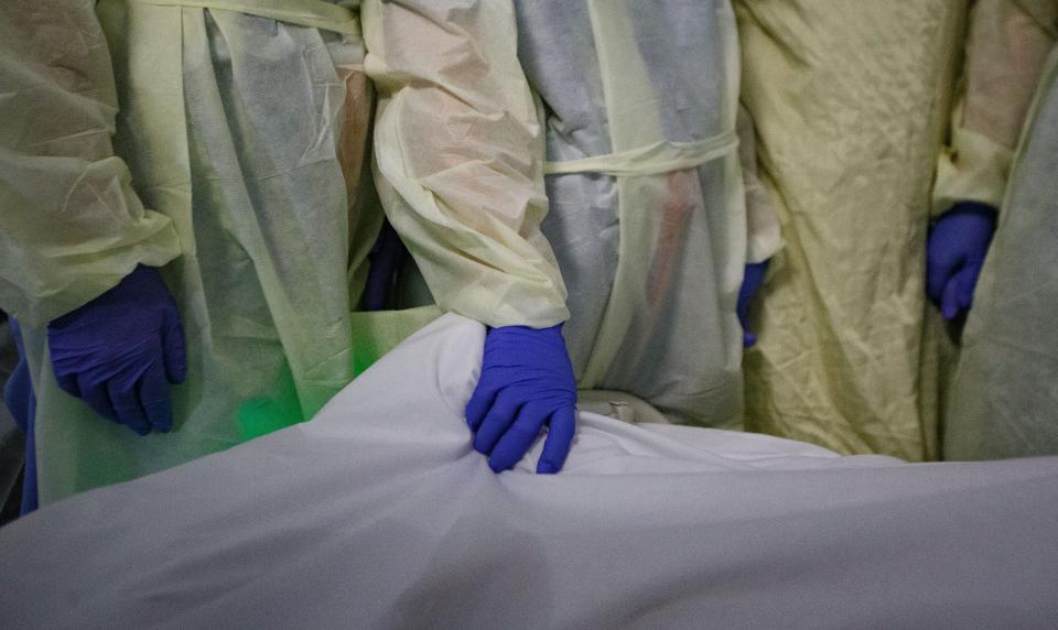 A nurse holds a Tallahassee Memorial HealthCare COVID patient's foot as others gather around his bedside to comfort him in his last moments Monday, Aug. 23, 2021.