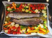Two fresh fish atop a bed of mixed vegetables ready for roasting