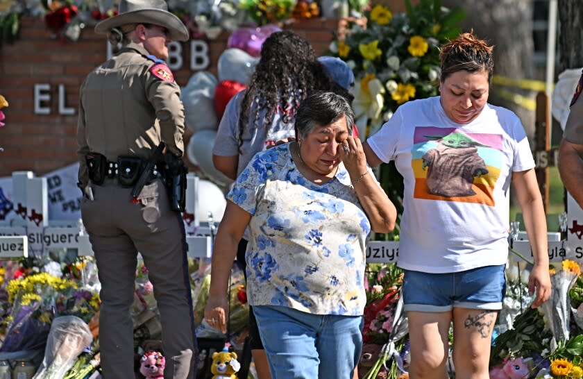 Uvalde, Texas May 26, 2022- Family members walk away after living flowers at a memorial outside Rob Elementary School in Uvalde, Texas. Nineteen students and two teachers died when a gunman opened fire in a classroom Tuesday. (Wally Skalij/Los Angeles Times)