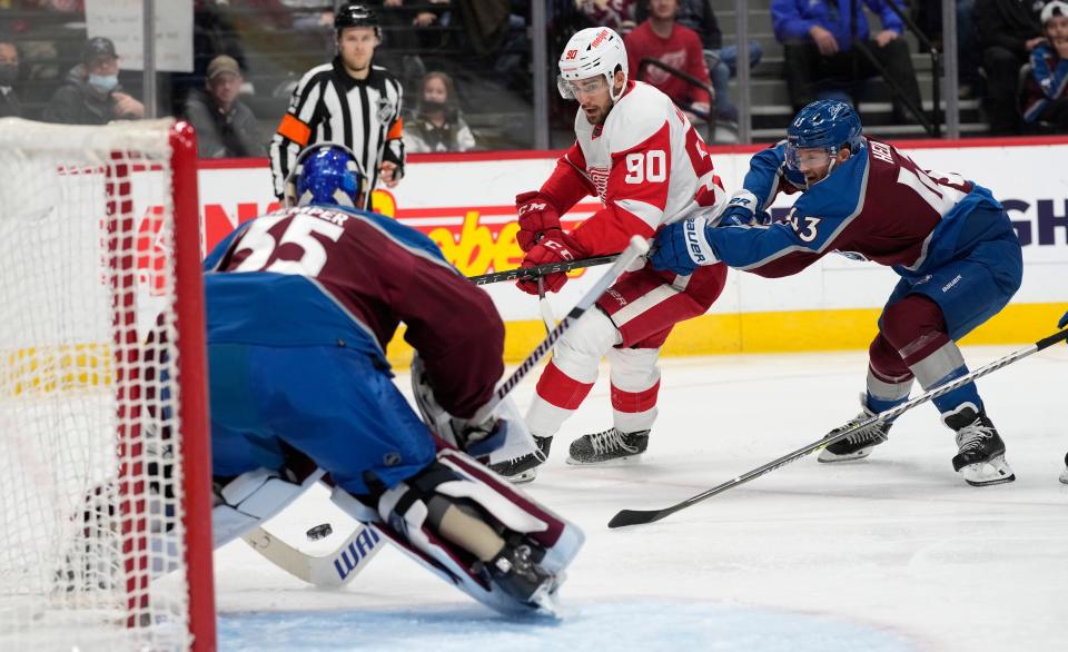 Detroit Red Wings center Joe Veleno, center, scores a goal against Colorado Avalanche goaltender Darcy Kuemper, left, after driving past Avalanche left wing Darren Helm (43) in the second period at Ball Arena in Denver on Friday, Dec. 10, 2021.