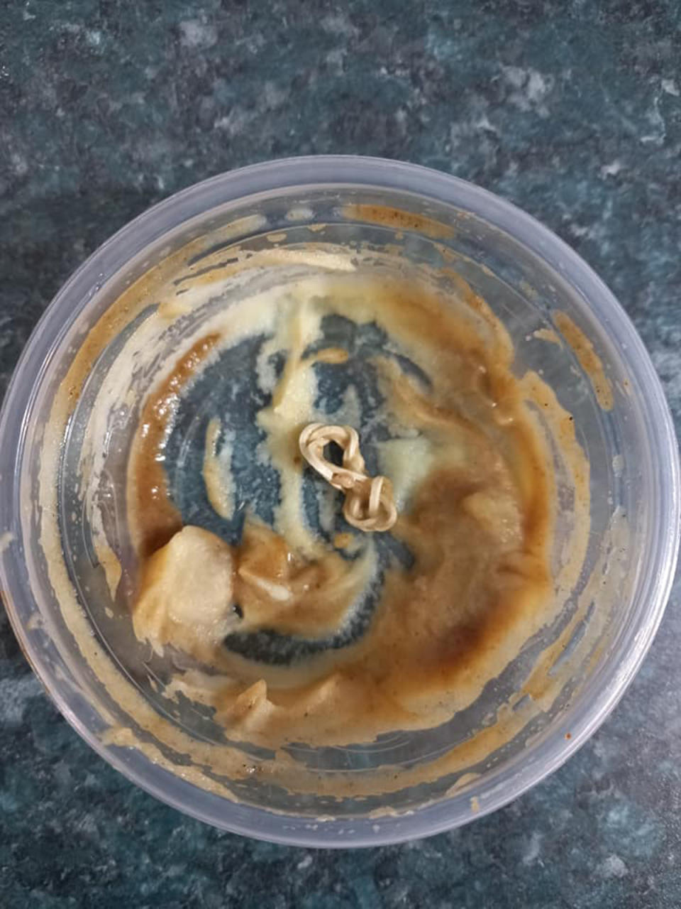 A KFC mash and gravy tub with an elastic band at the bottom.