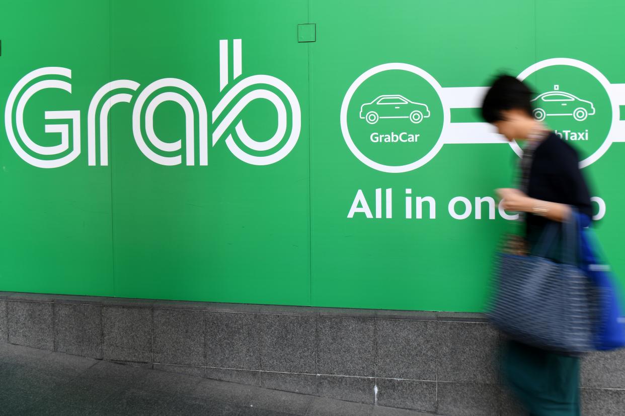 A woman walks past the Grab transport office in Singapore on September 24, 2018. - Singapore on September 24, fined ride-hailing firms Grab and Uber $9.5 million for breaking competition rules when they merged, saying the deal had increased fares and thrown up roadblocks for competitors. (Photo by ROSLAN RAHMAN / AFP)        (Photo credit should read ROSLAN RAHMAN/AFP via Getty Images)