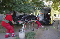 Medical workers load a body of a man killed during shelling in a yard of an apartment building in Kharkiv, Ukraine, Monday, June 27, 2022. (AP Photo/Andrii Marienko)