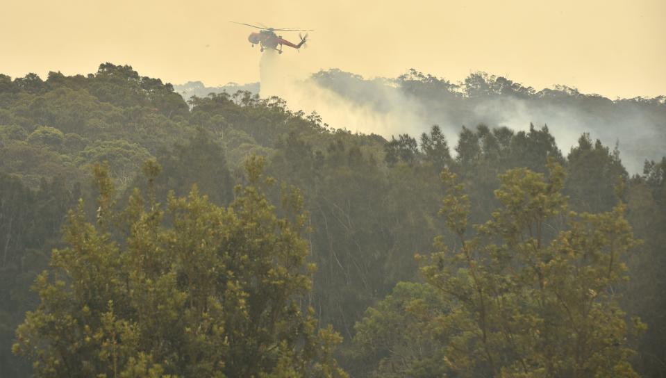 A helicopter drops water on a bushfire just outside Batemans Bay in New South Wales on Jan. 2, 2020. (Photo by PETER PARKS / AFP) (Photo by PETER PARKS/AFP via Getty Images)