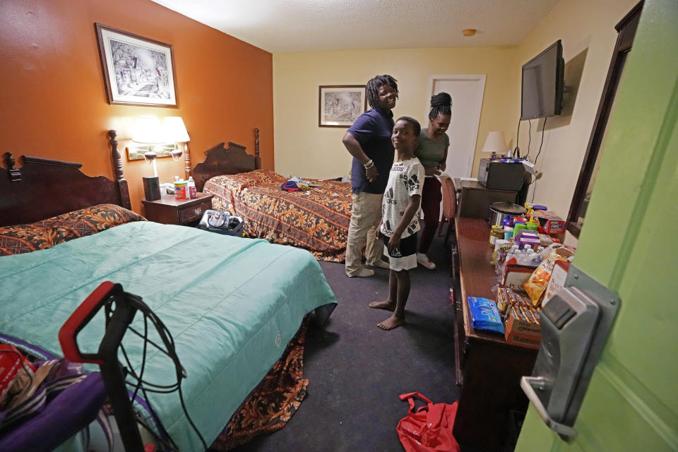 Ida Cartlidge, right, stands with her sons Jakavien, left, and Amarii on Nov. 29, 2023, in the middle of their two-bed motel room that serves as their temporary residence after a deadly tornado destroyed their home in March. The Cartlidge family of five spent nearly a year in the cramped motel room in search of a more permanent home, like many of their displaced neighbors. (AP Photo/Rogelio V. Solis)