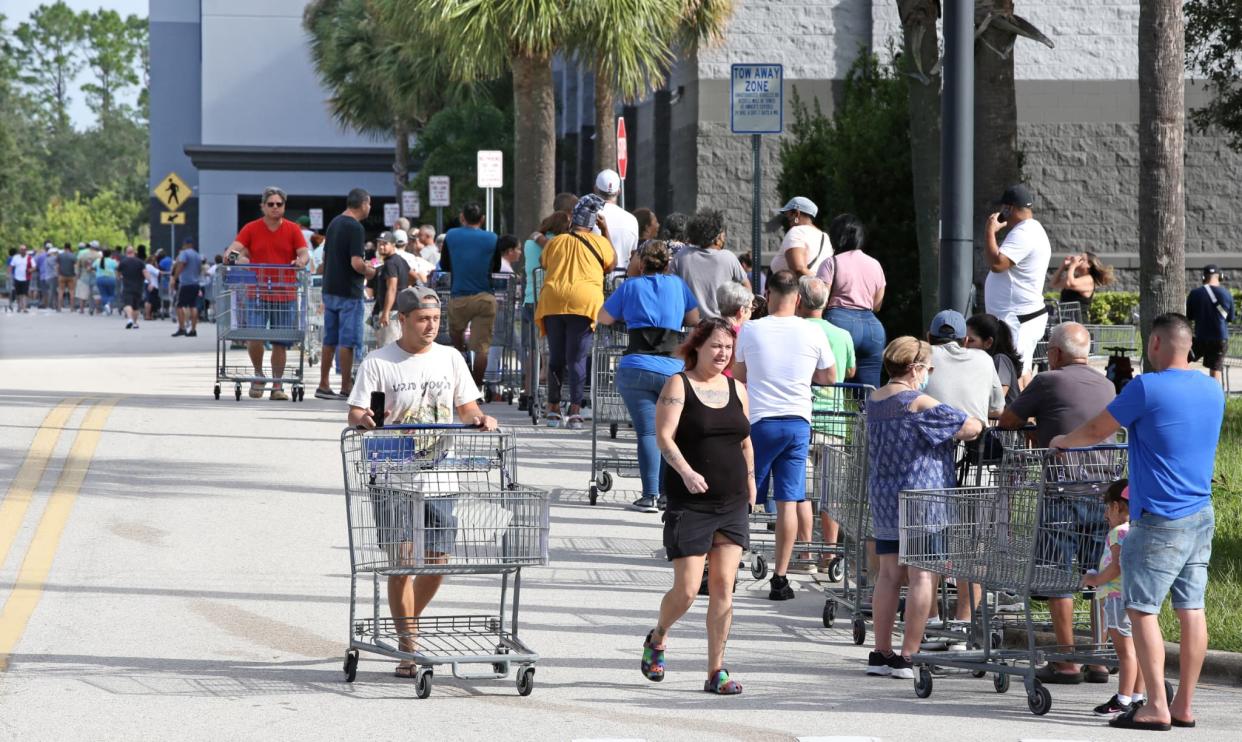 Des client marchent pour rejoindre une file d'attente s'étendant au-delà du parking à l'extérieur d'un entrepôt de vente au détail, alors que les gens se préparent à l'ouragan Ian, à Kissimmee, en Floride, le 25 septembre 2022. - Gregg Newton / AFP