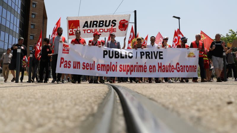 Employees of Airbus hold a banner reading "Not a single job lost in the Haute-Garonne" as they walk towards Toulouse-Blagnac airport during a strike called by unions in Blagnac