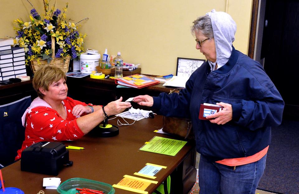 Jule E. Miller shows her photo ID to poll worker Jolene Dyer as Miller signs in to vote at the Frist Presbyterian Church in Wooster on Tuesday, May 2.