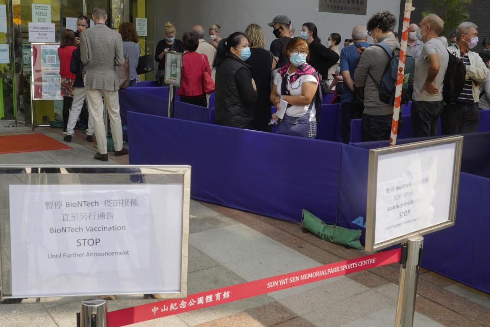 FILE - In this Wednesday, March 24, 2021 file photo, a notice of vaccine suspension, left, is placed as people queue up outside a vaccination center for BioNTech in Hong Kong. Hong Kong's sudden suspension of a COVID-19 vaccine developed by Pfizer and BioNTech is another blow to a vaccination program already struggling against a wall of public distrust. (AP Photo/Vincent Yu)