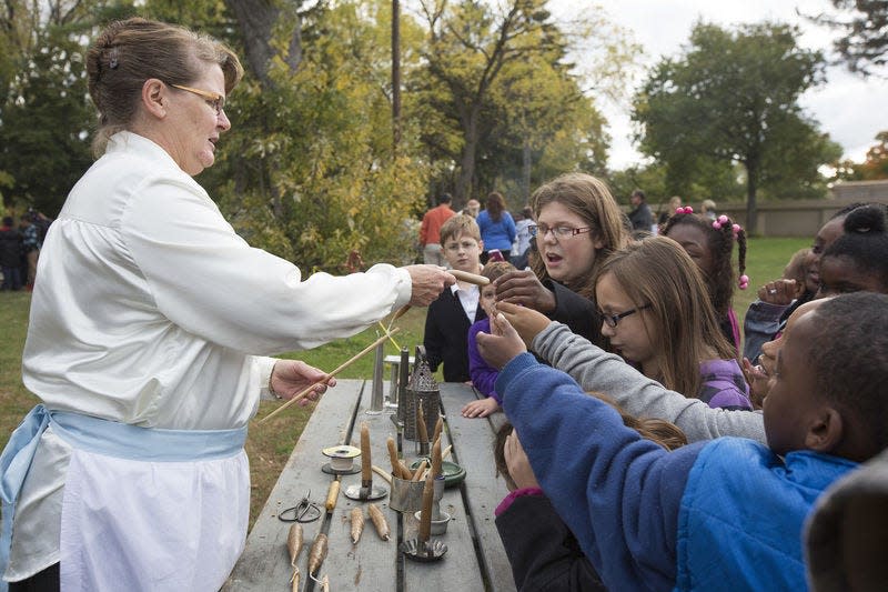 Judy Wheat, a volunteer with The History Museum, lets children touch candles she has just created through hand-dipping during a demonstration Oct. 14, 2015, at the Navarre Cabin in Leeper Park in South Bend.