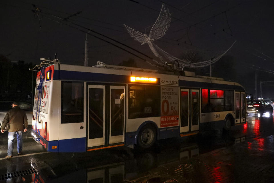 A man walks by a trolley bus that is stuck on a boulevard during a power outage in Chisinau, Moldova, Wednesday, Nov. 23, 2022. Moldova suffered massive power outages on Wednesday after Russian strikes on neighboring Ukraine's energy infrastructure left the small non-European Union country in the dark for the second time in little more than a week. (AP Photo/Aurel Obreja)