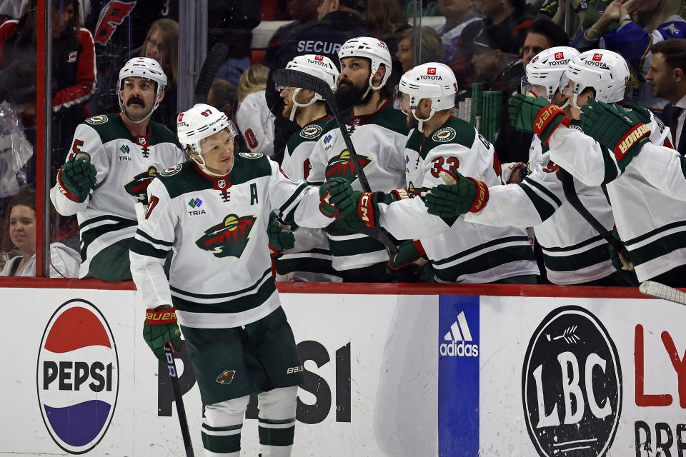 Minnesota Wild's Kirill Kaprizov celebrates his hat trick with teammates along the bench during the third period of an NHL hockey game against the Carolina Hurricanes in Raleigh, N.C., Sunday, Jan. 21, 2024. (AP Photo/Karl B DeBlaker)