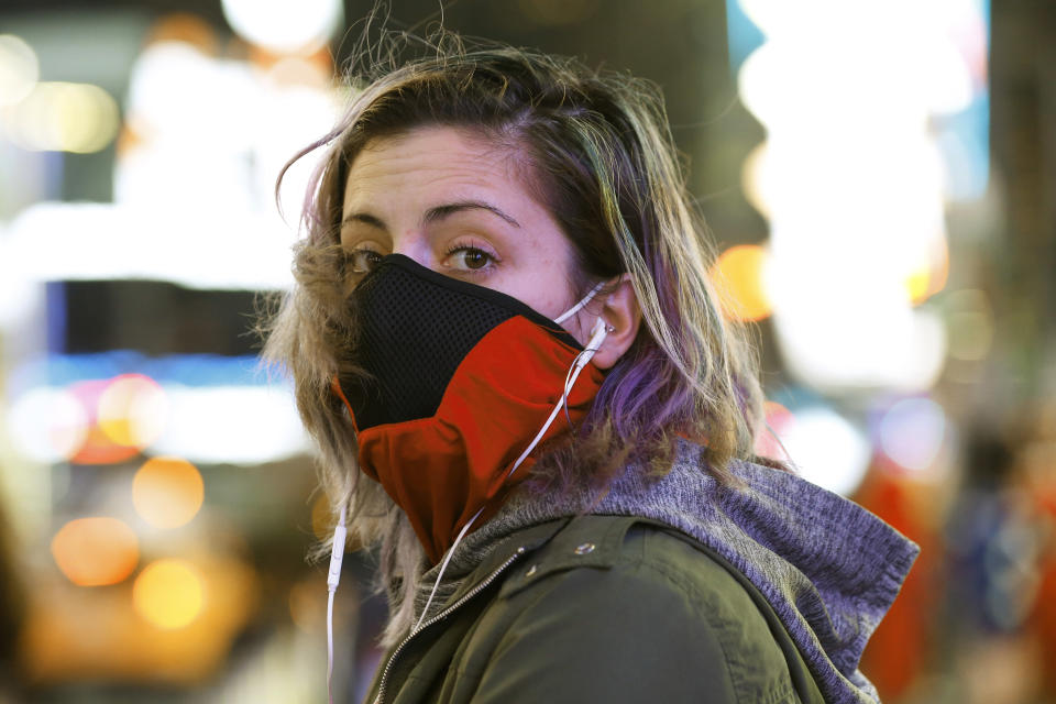 Brooklyn resident and waitress Casey Stewart peers out from a ski mask she adapted to protect herself from coronavirus after riding the subway to Times Square, Thursday, March 12, 2020, in New York to see for herself the virus outbreak's effect on the city. She is also wearing a protective mask beneath the ski mask. Stewart, who works at two restaurants, said she's definitely noticed a drop in the number of customers. She's also concerned because at least one of the places she works may have to close for at least a week or possibly longer. (AP Photo/Kathy Willens)