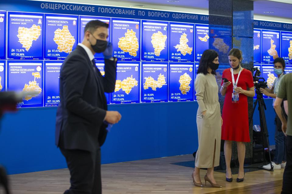 Staff members of the Russian Central Election Commission, wearing face masks and gloves to protect against coronavirus, gather prior to a news conference with Ella Pamfilova, head of Russian Central Election Commission, in front of an electronic screen showing the results of constitution vote in Moscow, Russia, Thursday, July 2, 2020. Almost 78% of voters in Russia have approved amendments to the country's constitution that will allow President Vladimir Putin to stay in power until 2036, Russian election officials said Thursday after all the votes were counted. Kremlin critics said the vote was rigged. (AP Photo/Alexander Zemlianichenko)