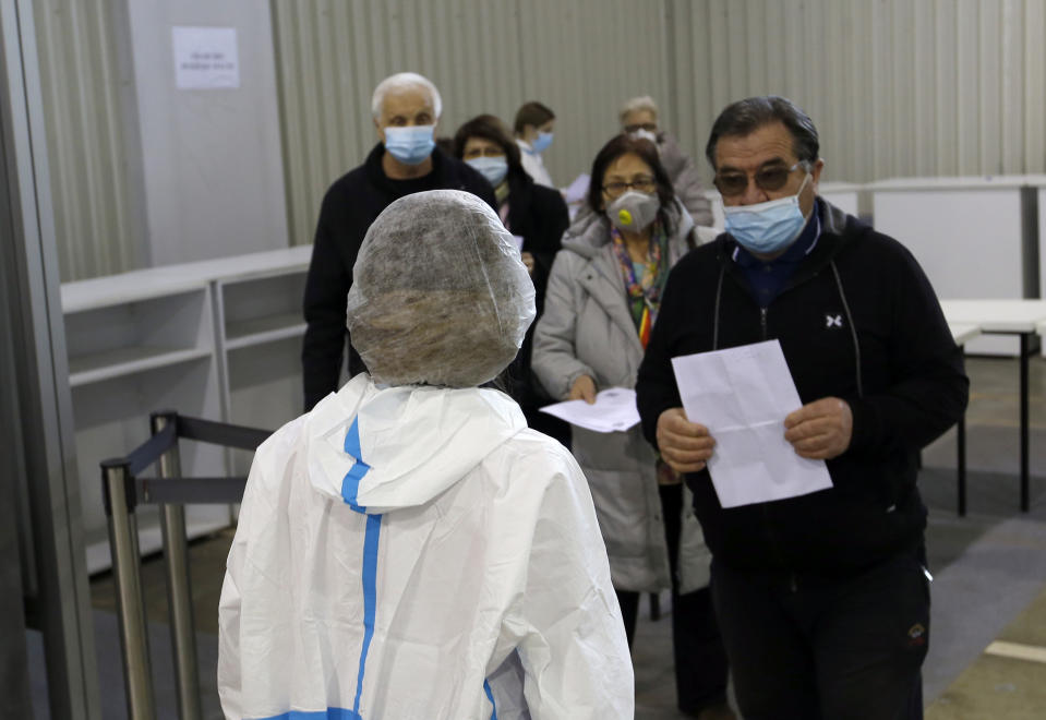 People wait in line to receive a dose of Chinese Sinopharm COVID-19 vaccine during the vaccination at Belgrade Fair makeshift vaccination center in Belgrade, Serbia, Wednesday, Feb. 17, 2021. Serbian health expert Chief epidemiologist Predrag Kon on Tuesday March 2, 2021, called for the government to introduce a state of emergency and a strict lockdown to halt a surge in coronavirus infections in the Balkan country. (AP Photo/Darko Vojinovic)