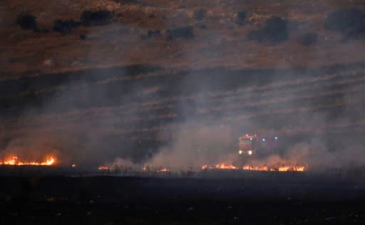 A firetruck puts out a blaze in a field on the Lebanese side of the border with Israel after the exchange of fire