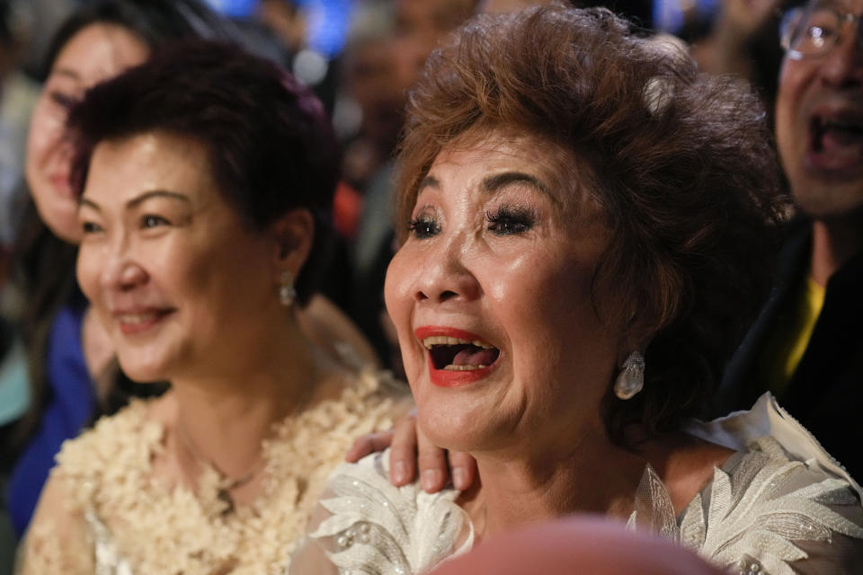 Janet Yeoh, right, mother of Michelle Yeoh, celebrates after her daughter won in the best actress category during the 95th Academy Awards in Los Angeles, as seen in a live view event at a cinema in Kuala Lumpur, Malaysia, Monday, March 13, 2023. (AP Photo/Vincent Thian)