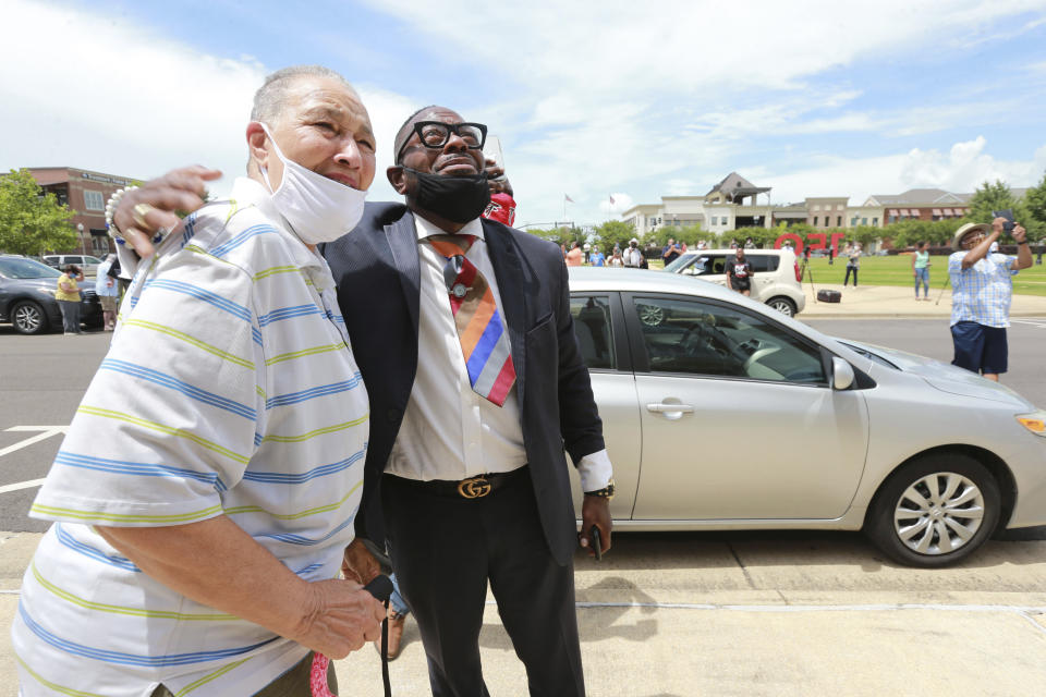 Tupelo City Councilwoman Nettie Davis, left, and Chris Traylor the President of the Lee County Chapter of the NCAA can only smile and cry as they watch the State Flag of Mississippi come down over the City Hall of Tupelo Mississippi Monday, June 29, 2020. Mississippi is retiring the last state flag in the U.S. that includes the Confederate battle emblem. (Thomas Wells/Northeast Mississippi Daily Journal, Via AP)