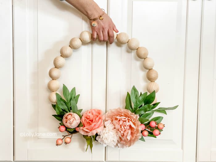 a wreath made out of large wooden beads and fake flowers