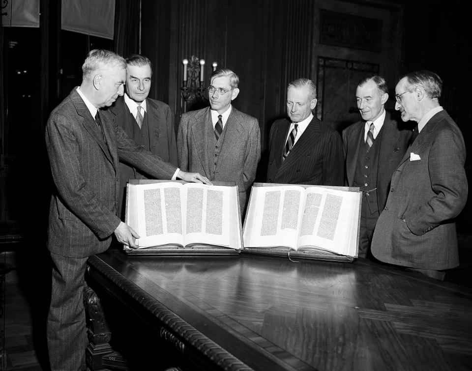 FILE - Members of the New York Public Library Board of Trustees pose for a photo with the first Gutenberg Bible to reach the U.S. 100 years prior, before it is placed on display in the lobby of the New York Public Library on Nov. 7, 1947. From left are Morris Hadley, Junius S. Morgan, Ralph A. Beals, Henry C. Taylor, Roland L. Redmond, and Dr. Albert Berg. The Bible was bought by book collector James Lenox for what was then considered the "mad" price of $2,600. (AP Photo/Ed Ford, File)