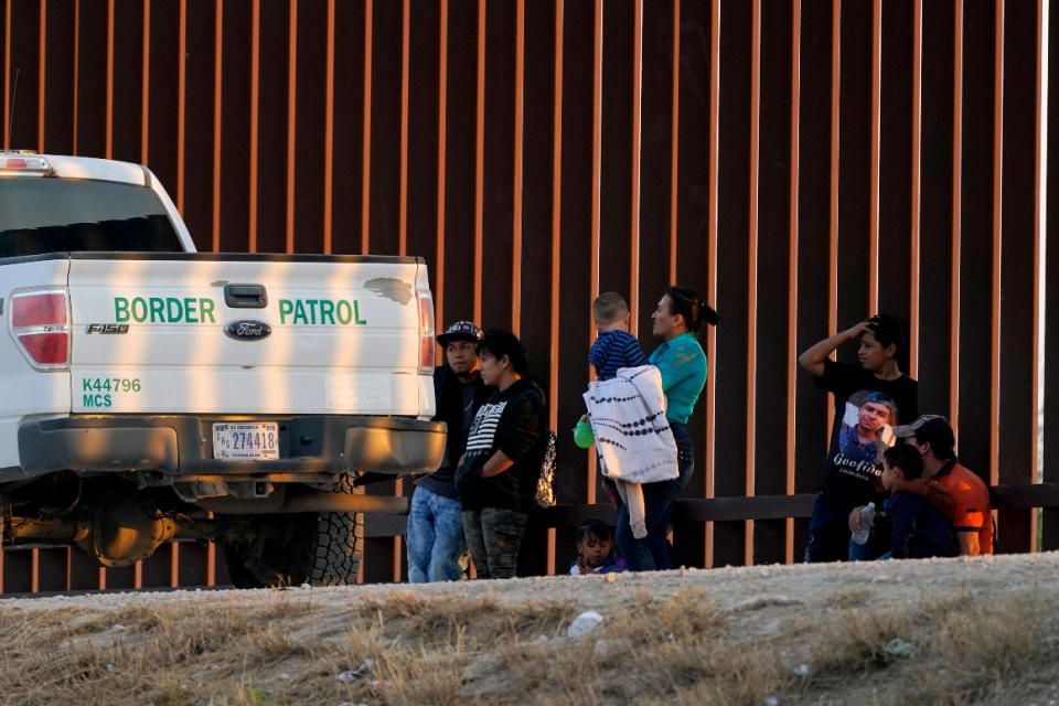 A U.S. Customs and Border Protection vehicle is seen next to migrants after they were detained and taken into custody, Sunday, March 21, 2021, in Abram-Perezville, Texas. 