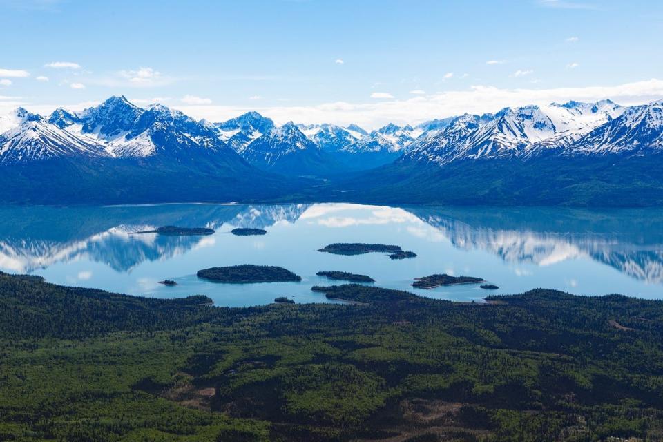 Mountains reflect on the still water of Lake Clark (Qizhjeh Vena) in summer.