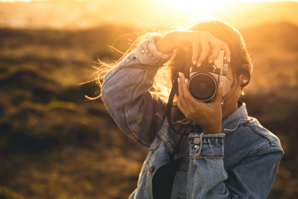 Beautiful woman taking picture outdoors with a analog camera