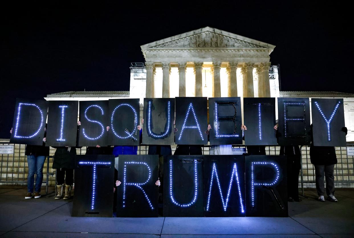 MoveOn members hold signs that say "Disqualify Trump" during a rally outside of the U.S. Supreme Court on Feb. 1, 2024 in Washington, D.C.