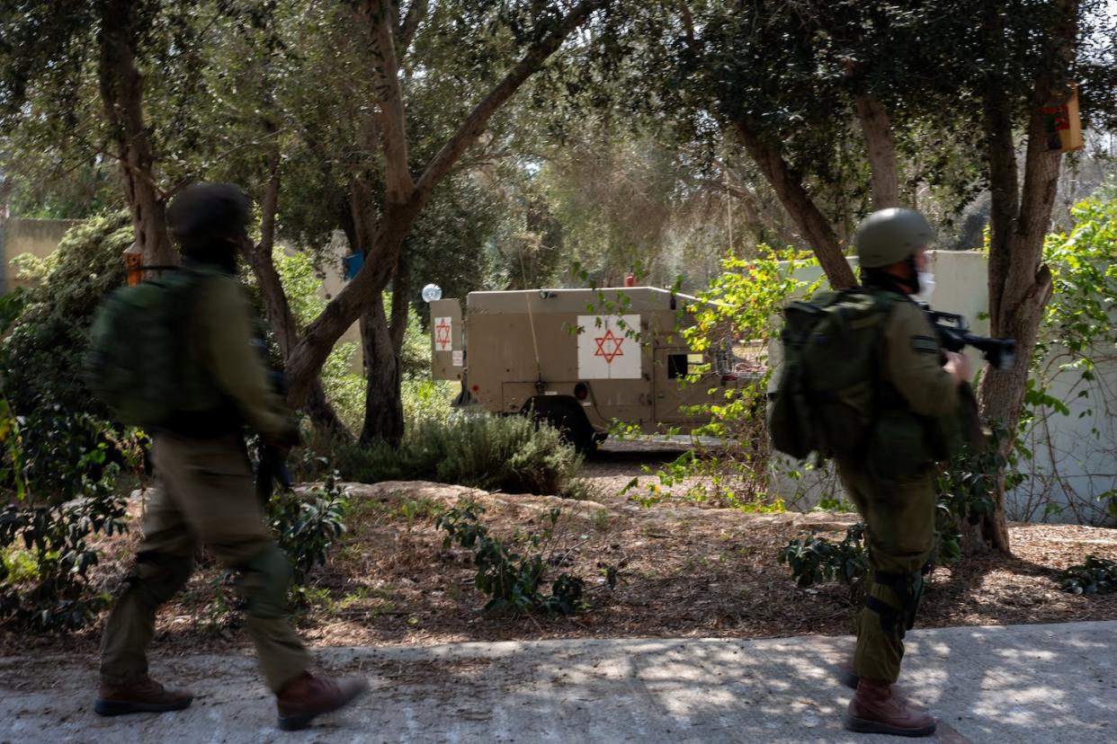 Des soldats israéliens passent devant un véhicule médical militaire le 10 octobre 2023 à Kfar Aza, un kibboutz où des militants du Hamas ont massacré de nombreux civils. <a href="https://www.gettyimages.com/detail/news-photo/soldiers-move-past-a-medical-idf-vehicle-at-kibbutz-kfar-news-photo/1728299509?adppopup=true" rel="nofollow noopener" target="_blank" data-ylk="slk:(Alexi J. Rosenfeld/Getty Images);elm:context_link;itc:0;sec:content-canvas" class="link ">(Alexi J. Rosenfeld/Getty Images) </a>