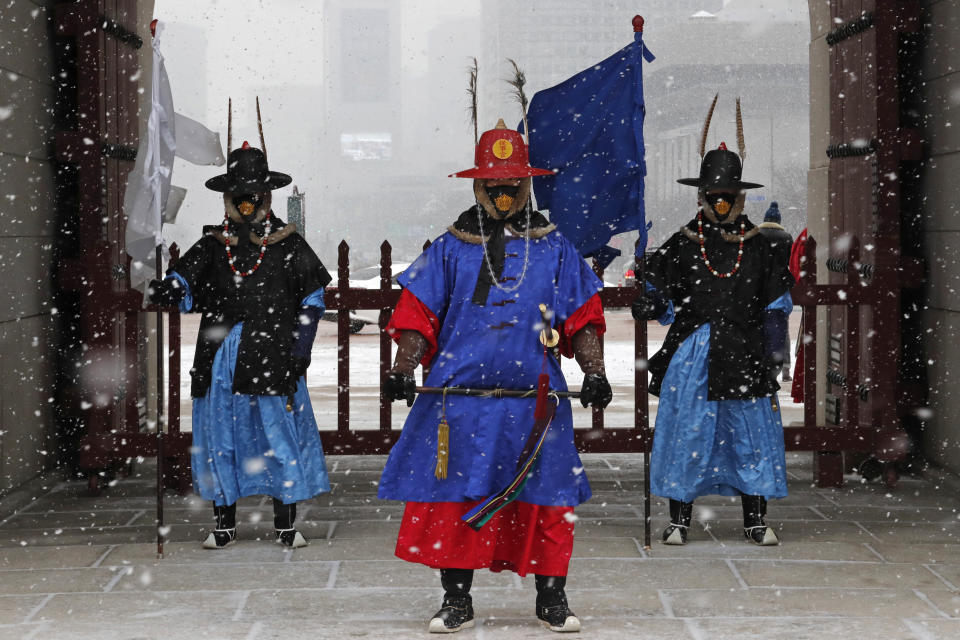 Guardias imperiales con mascarillas montan guardia durante una nevada ante el Palacio de Gyeongbok, el principal palacio real de la dinastía Joseon, en Seúl, Corea del Sur, el lunes 17 de febrero de 2020. (AP Foto/Ahn Young-joon)