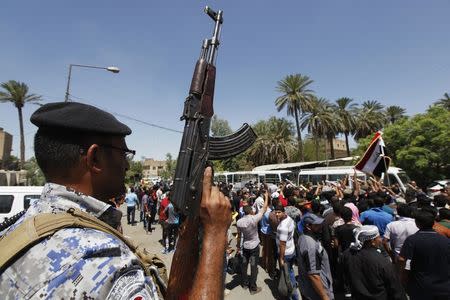 A member of Iraqi security forces stands guard near Shiite volunteers, who have joined the Iraqi army to fight against the predominantly Sunni militants from the radical Islamic State of Iraq and the Levant (ISIL) who have taken over Mosul and other northern provinces, in Baghdad, June 23, 2014. REUTERS/Ahmed Saad