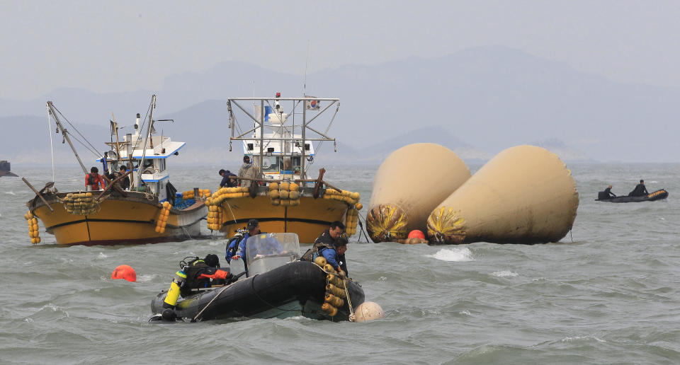 South Korean rescuers search for people believed to have been trapped in the sunken ferry Sewol near the buoys which were installed to mark the vessel in the water off the southern coast near Jindo, South Korea, Monday, April 21, 2014. Divers continued the grim work of recovering bodies from inside the sunken South Korean ferry Monday, securing a new entryway into the wreck, as a newly released transcript showed the ship was crippled by confusion and indecision well after it began listing. The transcript suggests that the chaos may have added to a death toll that could eventually exceed 300. (AP Photo/Ahn Young-joon)