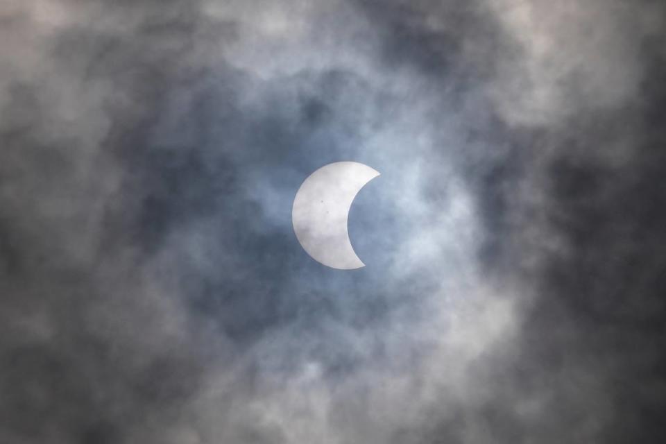 A partial solar eclipse is seen through the cloud over Jakarta, Indonesia.