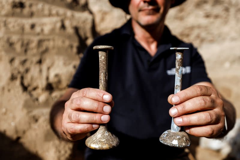 Pablo Betser de la IAA sostiene frascos de vidrio que probablemente se usan para guardar líquidos preciosos como aceites fragantes en el sitio de una excavación que se cree que data de la época del Sanedrín, a finales del siglo I y II d.C. según la Autoridad de Antigüedades de Israel, en Yavne, Israel 29 de noviembre de 2021.