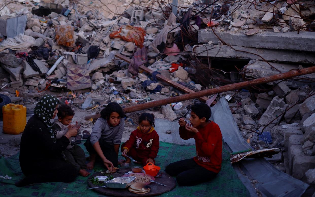 A family in Gaza eats surrounded by rubble