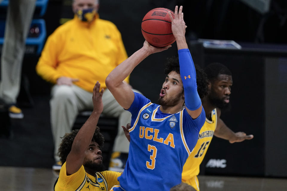 FILE - UCLA guard Johnny Juzang (3) shoots over Michigan guard Mike Smith, left, during the first half of an Elite 8 game in the NCAA men's college basketball tournament at Lucas Oil Stadium in Indianapolis, in this Tuesday, March 30, 2021, file photo. UCLA guard Johnny Juzang was selected to The Associated Press preseason All-America NCAA college basketball team, announced Monday, Oct. 25, 2021. (AP Photo/Michael Conroy, FIle)