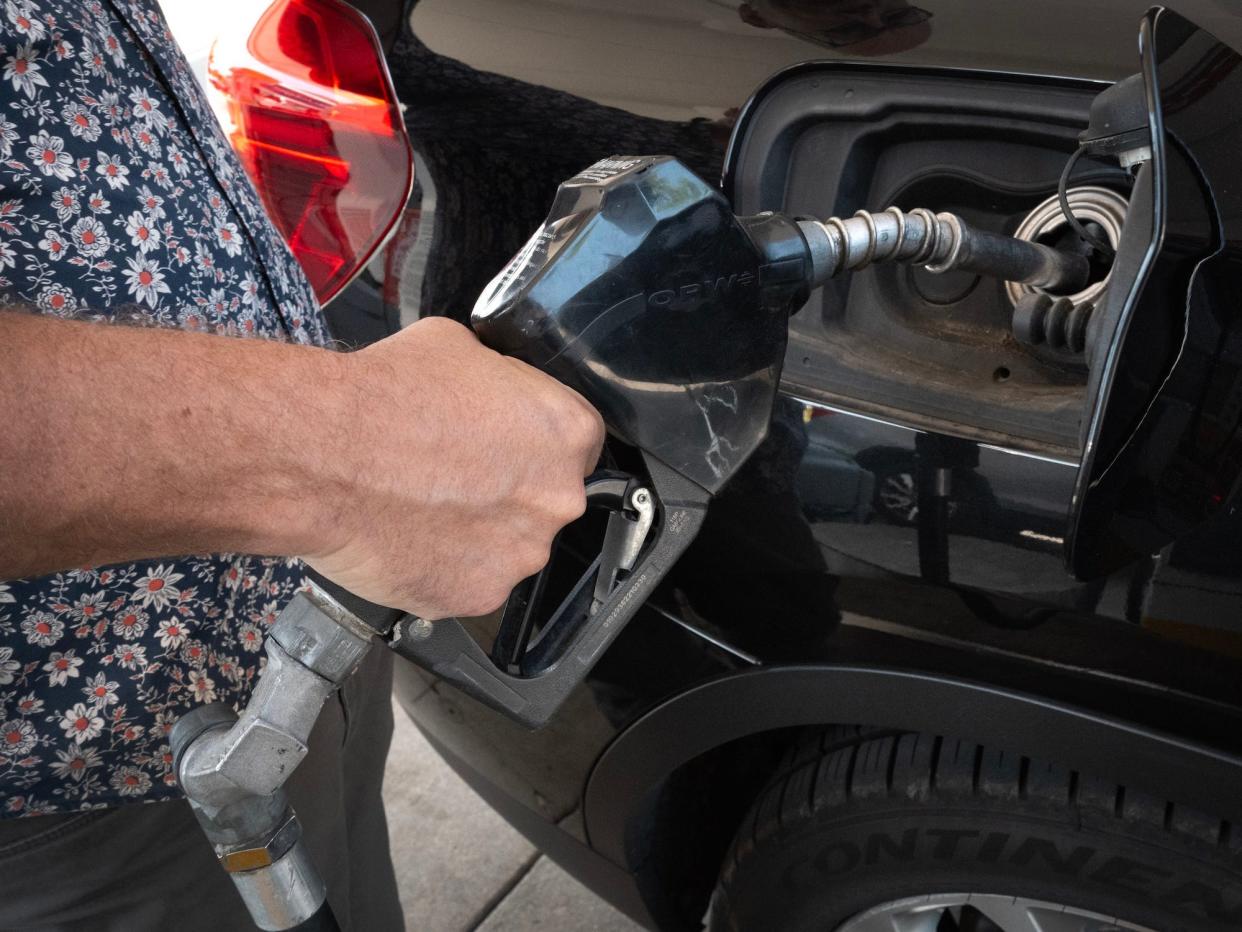 A close up of a customer pumping gas into their car.