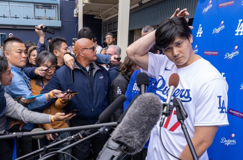 Shohei Ohtani, with scar from recent surgery on his arm, scratches his head while talking with media at DodgerFest 2024.