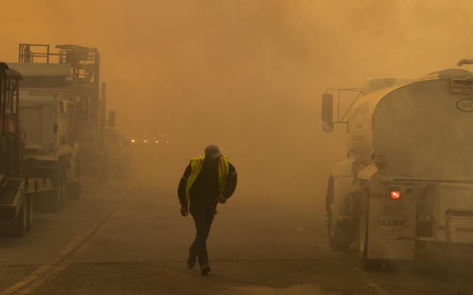 A water truck operator runs through the thick smoke of the advancing Silverado fire fueled by Santa Ana winds.