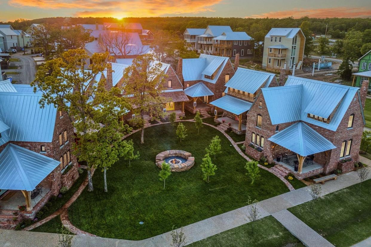 A neighborhood of closely clustered brick homes with sloped metal roofs and lights on inside.