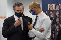 Gov. Gavin Newsom, left, speaks with Dr. Mark Ghaly, Secretary of the California Health and Human Services, at a news conference in Oakland, Calif., Monday, July 26, 2021. California will require state employees and all health care workers to show proof of COVID-19 vaccination or get tested weekly. Officials are tightening restrictions in an effort to slow rising coronavirus infections in the nation's most populous state, mostly among the unvaccinated. (AP Photo/Jeff Chiu)