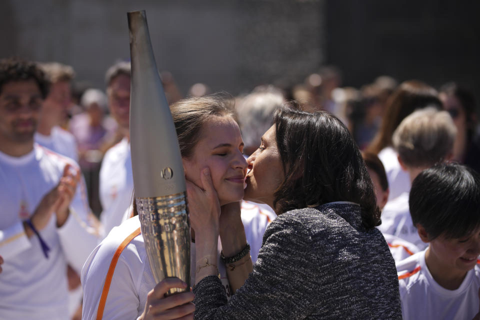 French Sports Minister Amelie Oudea-Castera, right, kisses Maria Vysotchanska of Ukraine on the cheek during the Olympic torch relay in Marseille, southern France, Thursday, May 9, 2024. Torchbearers are to carry the Olympic flame through the streets of France' s southern port city of Marseille, one day after it arrived on a majestic three-mast ship for the welcoming ceremony. (AP Photo/Daniel Cole)