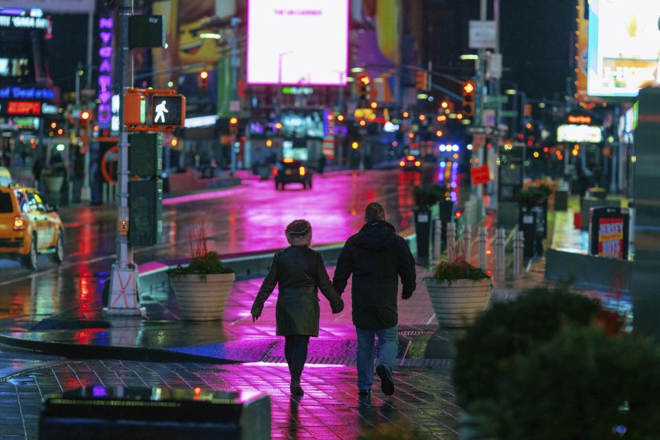 A couple walks through Times Square in the early morning Sunday, Jan. 20, 2019, in New York. The National Weather Service said on Saturday that a dramatic drop in temperatures could turn the weekend's rainfall into ice before Monday. (AP Photo/Kevin Hagen)