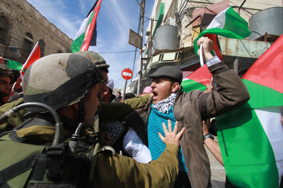 Palestinians scuffle with Israeli soldiers during a demonstration against the closure of the main downtown street in the center of the West Bank city of Hebron, Friday, Feb. 21, 2014. Shuhada street was shut after a 1994 mosque massacre when a settler shot and killed 29 Muslim worshippers. The military closed it citing security reasons. (AP Photo/Nasser Shiyoukhi)