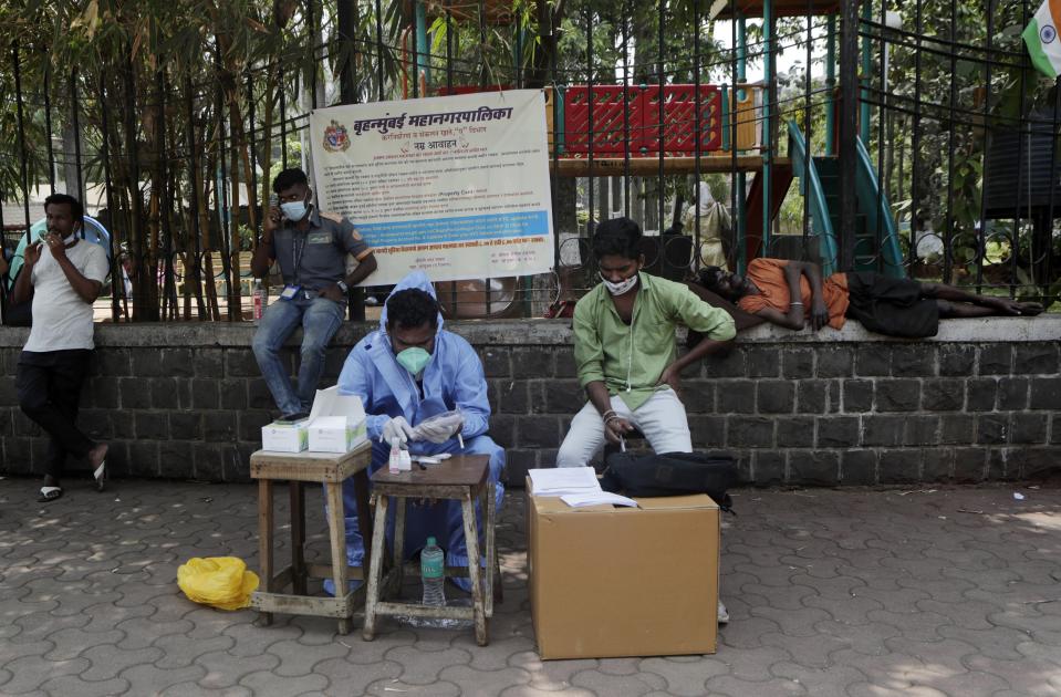 A health workers waits to conduct tests for COVID-19 at a roadside camp in Mumbai, India, Thursday, March 25, 2021. (AP Photo/Rajanish Kakade)