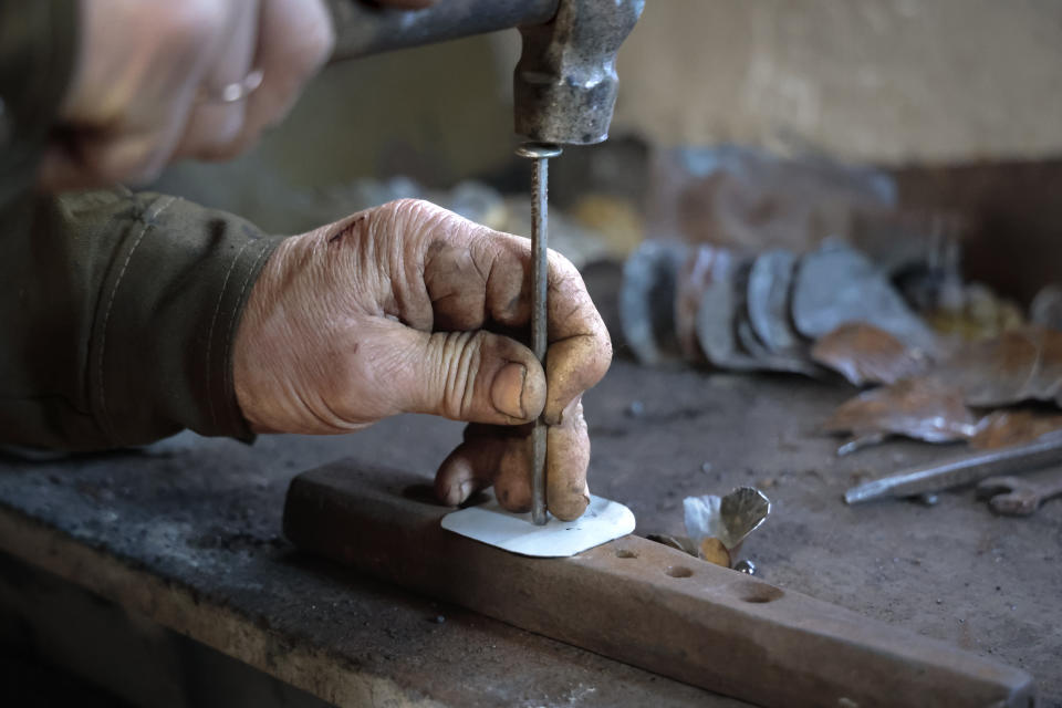 Viktor Mikhalev works in a workshop in his house in Donetsk, Russian-controlled Donetsk region, eastern Ukraine, Saturday, March 4, 2023. Mikhalev is transforming weapons and ammunition into flowers of war. Mikhalev, trained as a welder, lives and works in a house whose fence and door are decorated with forged flowers and grapes. (AP Photo/Alexei Alexandrov)