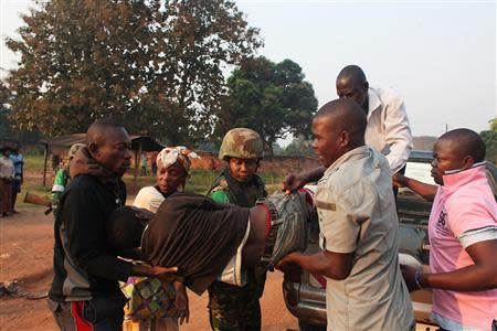 A man wounded in overnight clashes is assisted by peacekeepers and family members in a neighbourhood in Bangui December 23, 2013. REUTERS/Andreea Campeanu