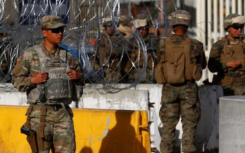 US Marines stand guard next to a barricade at the border in Tijuana - Credit: Reuters